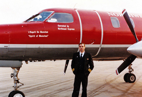 a man in a uniform standing next to a plane